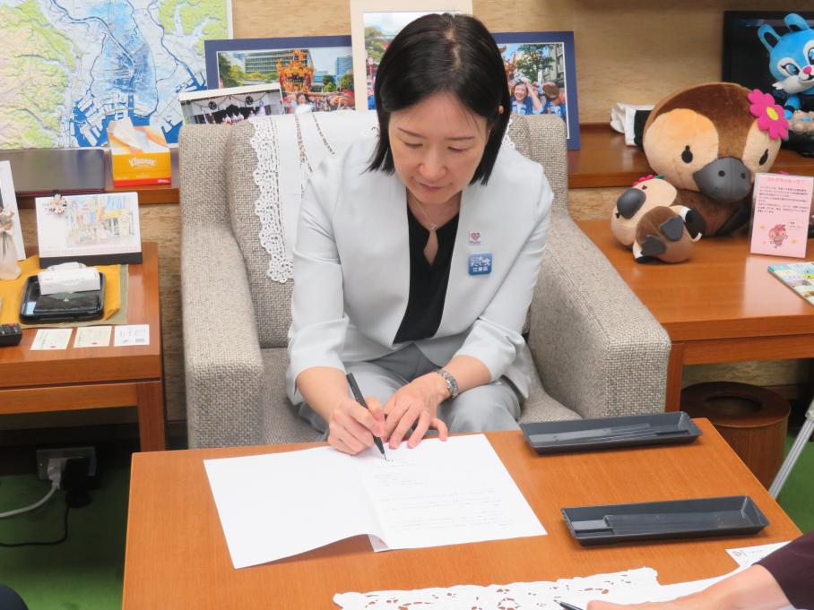 区長が協定書に署名する様子
