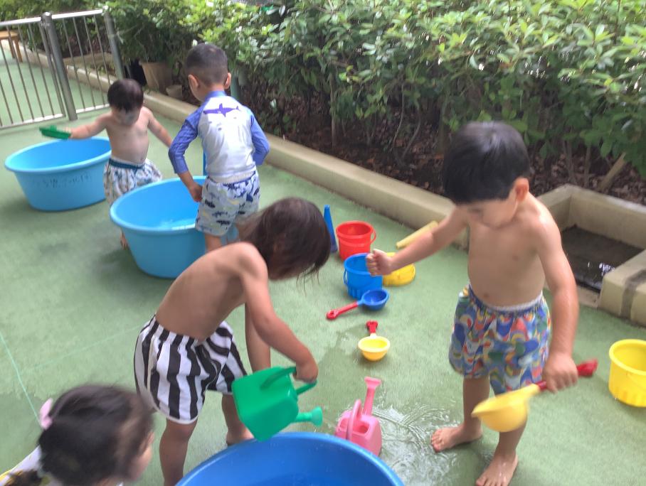 2歳児クラスみかん組ジョウロを使用した水遊びの様子