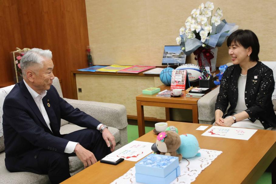 笑顔で歓談する木村区長と大和田代表取締役。机の上には区のゆるキャラ・コトミのぬいぐるみとトーヨーカネツのキャラクターのぬいぐるみ