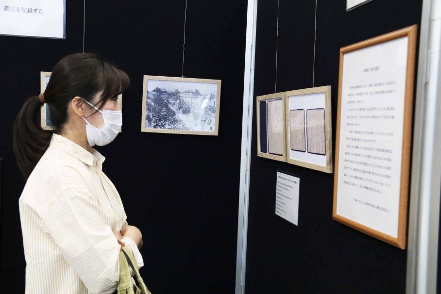 額物に入れられて壁に掲示されている、小津の父が所持していた手帳の写しに見入る女性の写真
