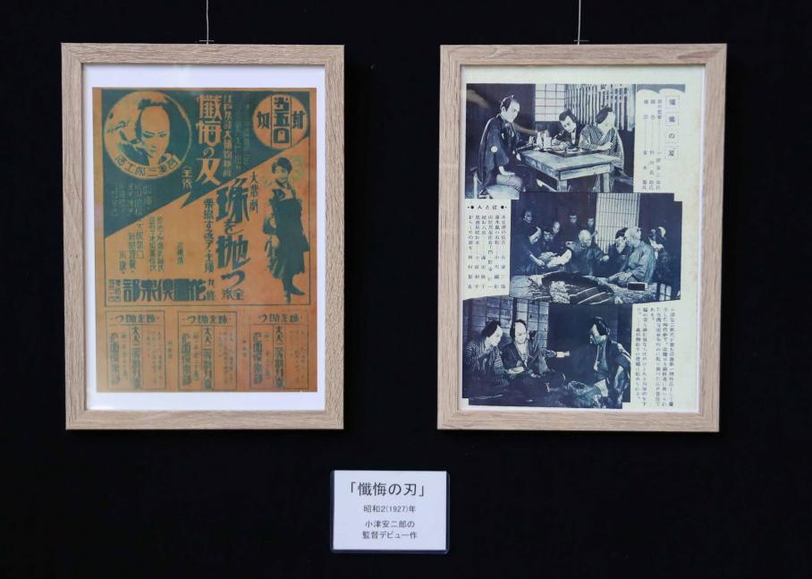 小津のデビュー作「懺悔の刃」の複製資料。左側にはオレンジと緑が基調の人物ポスターが掲示され、右側には作品の3つの場面写真が掲示