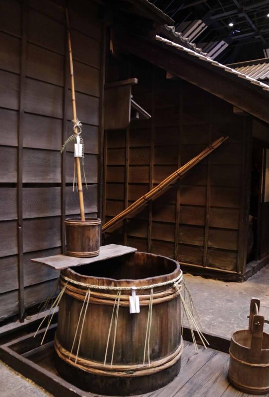 家屋に隣接したこげ茶色の木造の井戸。井戸には、紙垂の付いた細い注連飾りがまかれている。