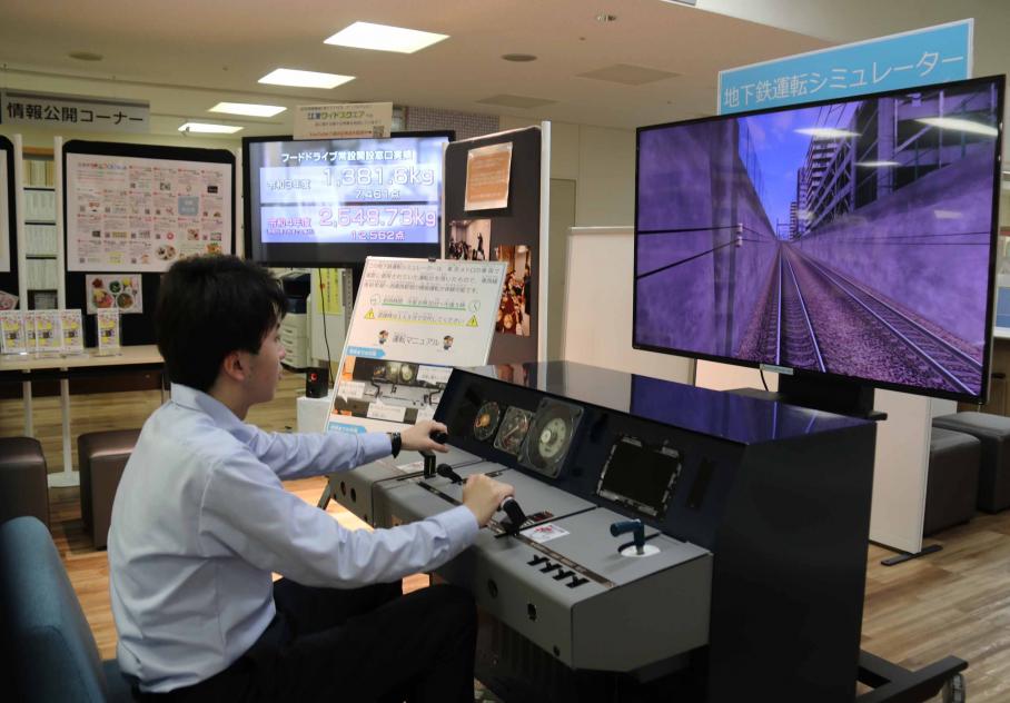 こうとう情報ステーションに設置されている地下鉄シミュレーターを座りながら操作する男性