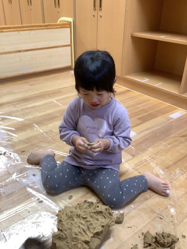 2さいじくらすがつちねんどにふれているようす