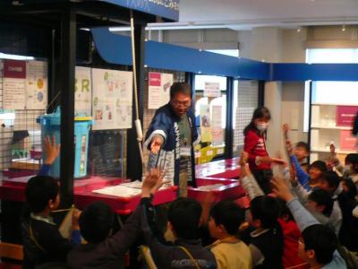 小学校の社会科見学受け入れの様子。人気の展示「ごみの重さ体験」を案内するエコサポーター。