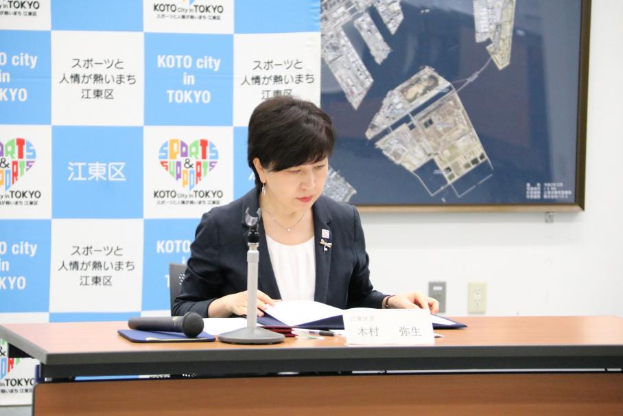 机上で協定書を開き内容を確認する紺のスーツ姿の木村区長