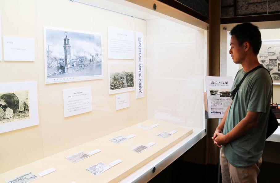 関東大震災の被害状況が写された絵葉書の展示コーナーを見る男性の写真
