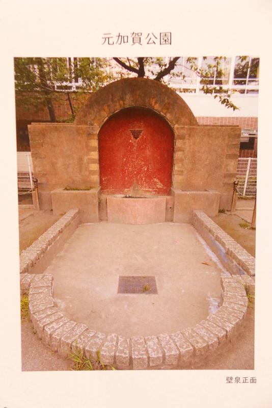 元加賀公園の壁泉の写真。左右は長方形、中央はアーチになっているコンクリートの壁に噴水がついているように見える。