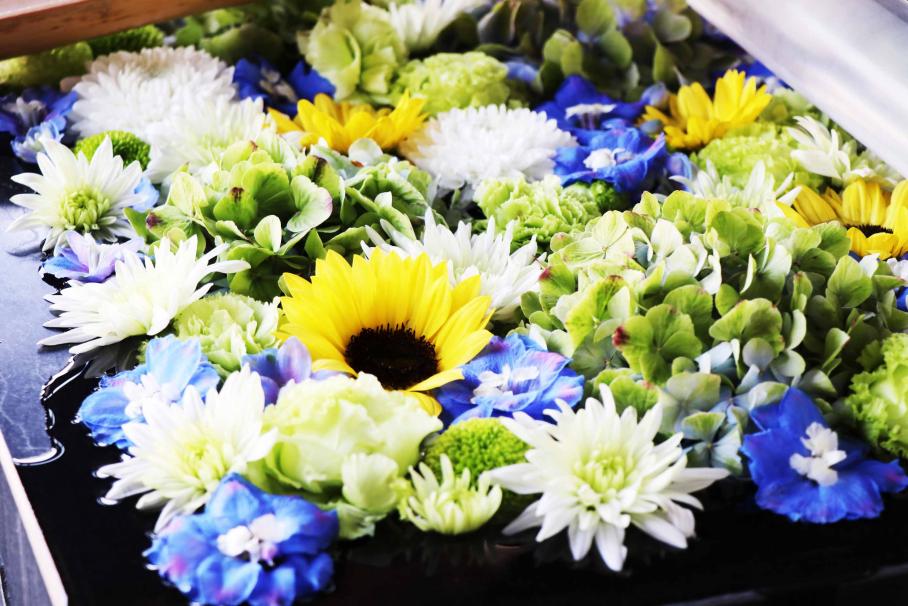 黄色いヒマワリや白い菊のような花、青い花が浮かぶ涼しげな花手水（深川不動堂）