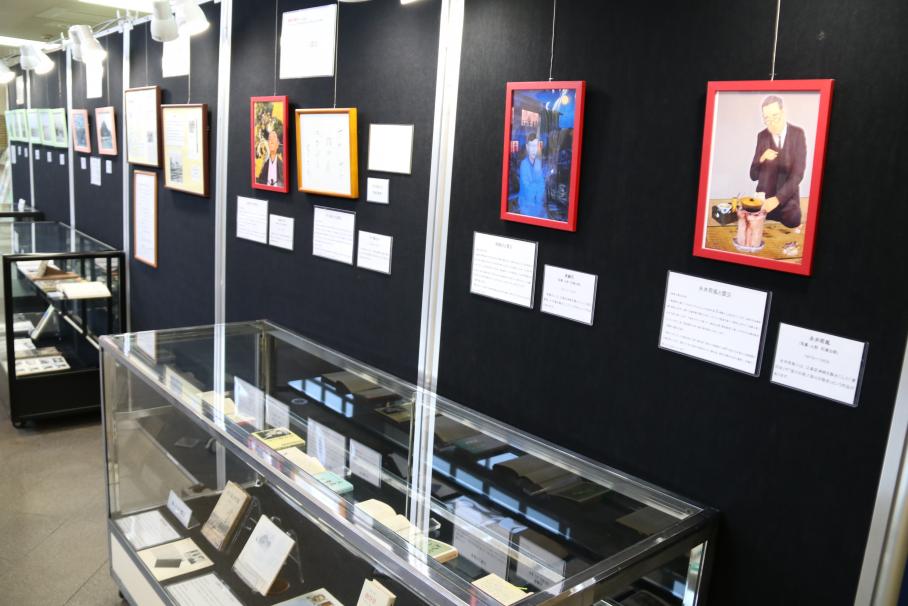 泉鏡花、谷崎潤一郎などの作品や資料が陳列されたショーケース。壁には各文豪のカラフルな人形写真が掲示されている。
