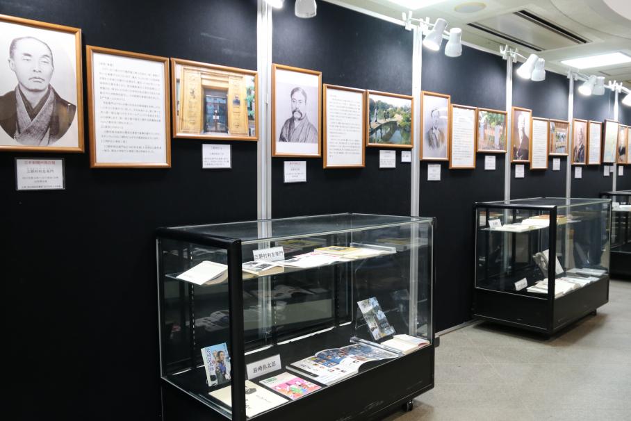 岩崎や三野村といった経済人たちの白黒の肖像画、解説パネルなどが掲示され、下には関連図書などの展示されているショーケースがある